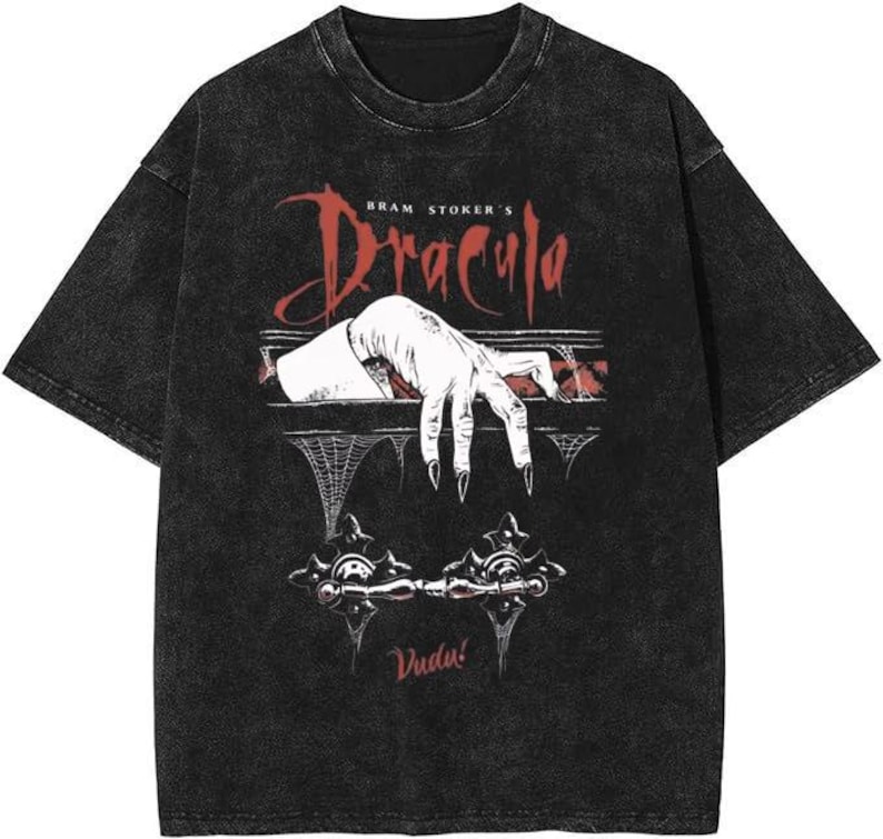 May include: Black t-shirt featuring a graphic from Bram Stoker's Dracula. The design includes a white hand with long black fingernails reaching out, with the word "Dracula" in red script. The shirt also has the word "Vudu!" printed on it.