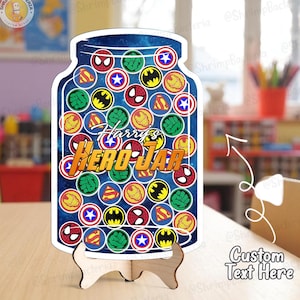 May include: A wooden jar-shaped sign with a blue background filled with superhero logos. The sign reads "Harry's HERO JAR" in a colorful font and is displayed on a wooden stand. The words "Custom Text Here" are also visible.