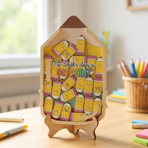 Puede incluir: Expositor de madera con forma de lápiz con fondo amarillo y numerosos recortes de lápices amarillos. El texto "Ms. Smith's class is ON POINT" es visible. El expositor está sostenido por un soporte de madera.