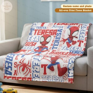 Może przedstawiać: Biały koc z polaru z czerwono-niebieskim wzorem Spider-Mana i powtarzającym się imieniem "Teresa". Koc ma opcję niestandardowego imienia i zdjęcia i jest "All-over Print Fleece Blanket".