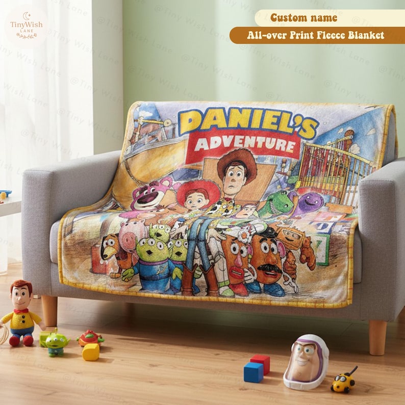 May include: A fleece blanket featuring a colorful graphic print of various animated toy characters, including a cowboy, a cowgirl, and aliens. The text "DANIEL'S ADVENTURE" is printed in large yellow and red letters across the top of the blanket.