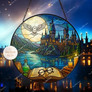 Può includere: Vetrata rotonda raffigurante una scena di castello con luna piena, gufo e lago. Un libro aperto con occhiali e una bacchetta magica è in primo piano. La finestra è sospesa da una catena.