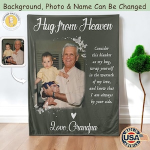 May include: A personalized blanket with a photo of a man holding a baby. The blanket has the text "Hug from Heaven" and a message from "Grandpa". The blanket is made in the USA.