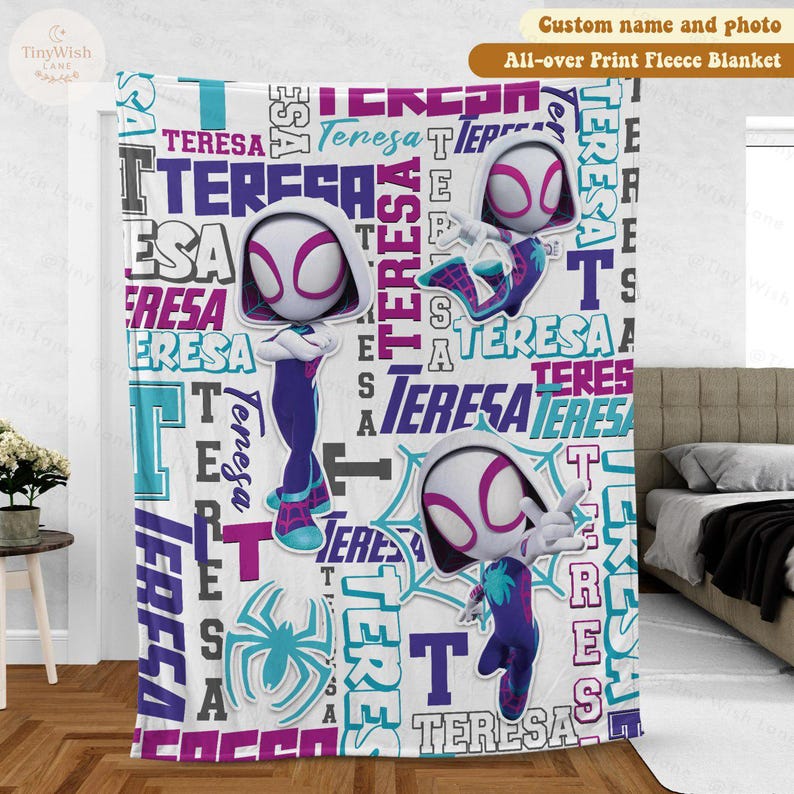 Może przedstawiać: Koc z nadrukiem na całej powierzchni z motywem Spider-Gwen i imieniem "Teresa" w powtarzającym się wzorze. Koc ma białe tło z turkusowymi, fioletowymi i czarnymi akcentami. Przytulny element wystroju domu.