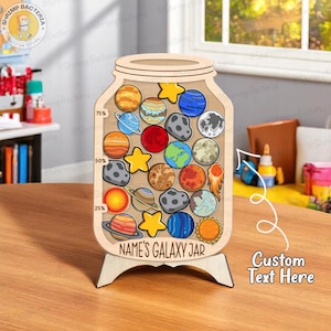 Puede incluir: Un tarro de galaxia de madera con recortes coloridos de planetas y estrellas. El tarro tiene un soporte de madera y el texto "NAME'S GALAXY JAR" es visible. El tarro tiene una escala del 25% al 75% y las palabras "Custom Text Here" también son visibles.