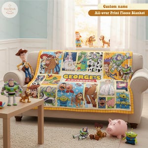 May include: A fleece blanket with a colorful all-over print featuring characters from a popular animated movie. The blanket is draped over a beige sofa, with the text "GEORGE'S ADVENTURE" visible. The blanket has a yellow border.