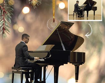 Peut inclure: Ornement de Noël en forme de piano à queue noir avec une ficelle dorée. L'ornement présente une image d'une personne jouant du piano. L'arrière-plan est flou avec des lumières bokeh.
