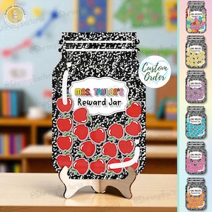 Puede incluir: Un tarro de recompensas de madera con forma de página de cuaderno con el texto "MRS. TAYLOR'S Reward Jar". El tarro está decorado con ilustraciones de manzanas rojas y se apoya en un soporte de madera. Se muestran diseños de tarros adicionales.