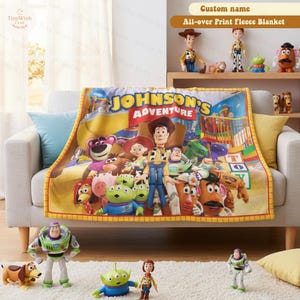 May include: A fleece blanket featuring a colorful graphic print of various animated characters from the Toy Story franchise, with the text JOHNSON'S ADVENTURE prominently displayed in yellow and white letters across the top center.