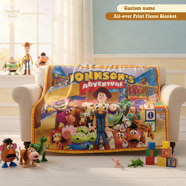 May include: A fleece blanket featuring a colorful all-over print of various animated toy characters and the text Johnson's Adventure. The blanket is draped over a sofa, surrounded by several plastic toy figures and colorful alphabet blocks.