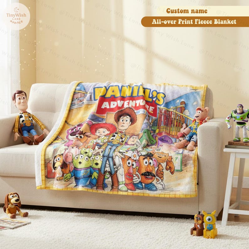 May include: A fleece blanket featuring a colorful graphic print of various animated toy characters, including a cowboy, a potato-shaped figure, and green aliens. The text on the blanket reads "[Name]'s Adventure" in bold yellow and red letters.