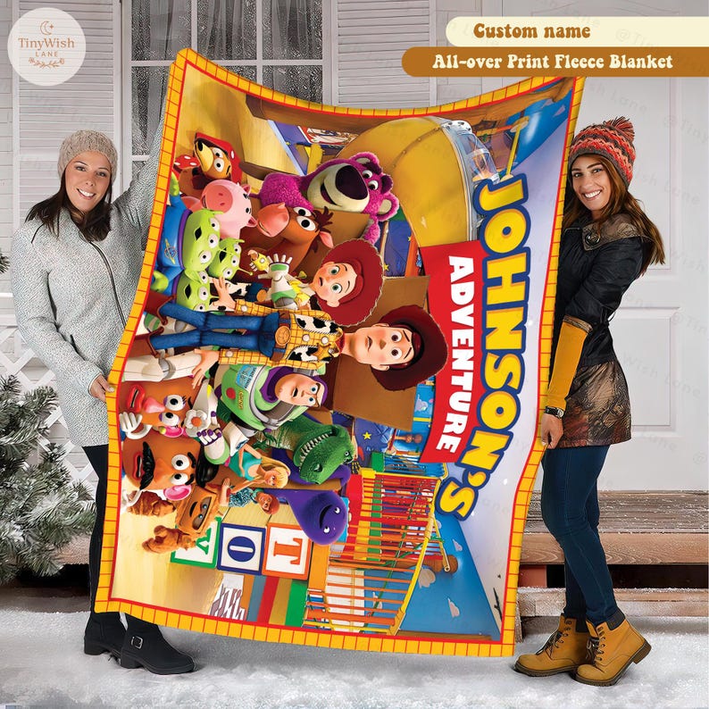 May include: A fleece blanket featuring a colorful graphic print of various animated toy characters, including a cowboy, space ranger, and bear, with the text "JOHNSON'S ADVENTURE" printed in large yellow letters on a red background.