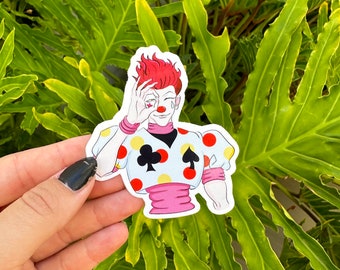 May include: A sticker featuring a cartoon character with red hair, a white and red polka dot shirt, and a black spade on the chest. The character is holding a playing card in front of their eye.