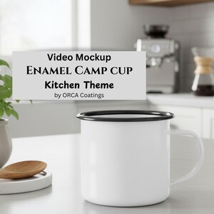 May include: A white enamel camp cup with a black rim and handle. The cup is in a kitchen setting, with text that reads "Video Mockup ENAMEL CAMP CUP Kitchen Theme by ORCA Coatings."