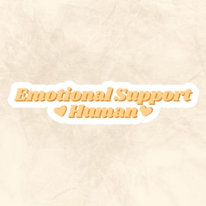 May include: A white sticker with the text "Emotional Support Human" in orange with two orange hearts on either side of the word "Human".