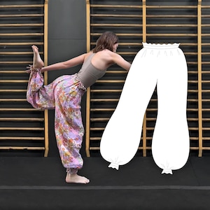 Puede incluir: Un pantalón estampado con un diseño floral en rosa, naranja y amarillo. El pantalón tiene cintura fruncida y puños en los tobillos. También se muestra una ilustración blanca del pantalón.