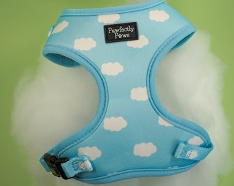 May include: A blue dog harness with white clouds printed on it. The harness has a black label that says "Pawfectly P&ws".