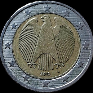 May include: A two-euro coin with a central eagle design, dated 2010. The coin has a silver outer ring with twelve stars and a gold-coloured centre. The eagle is a detailed and prominent feature.