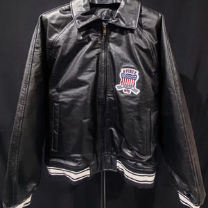 May include: A white ceramic mug with a black handle and the text "But First, Coffee" in a black, bold font. The mug is on a white surface. The mug is approximately 4 inches tall.