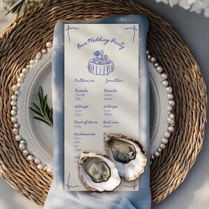 Könnte beinhalten: Eine Hochzeitstafel mit einem geflochtenen Platzset, einem weißen Teller mit Perlenbesatz und einer blauen Serviette. Die Tischdekoration umfasst eine Menükarte mit dem Text "Our Wedding Party" und zwei Austern.