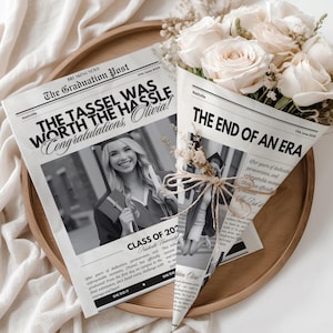 Könnte beinhalten: Eine Abschluss-Arrangement mit einem Strauß weißer Rosen, eingewickelt in Zeitungspapier. Die Schlagzeilen lauten „The Tassel Was Worth The Hassle“ und „The End of an Era“. Auf einem Holztablett, mit weißem Stoff im Hintergrund.