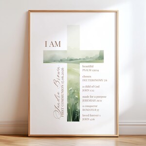 Könnte beinhalten: Ein gerahmter vertikaler Druck mit einer Kreuzform, die mit einer Aquarell-Landschaft aus grünen Feldern und Blumen gefüllt ist. Der Text lautet I AM, Jandra Brown, FIRST COMMUNION 17.06.2026 sowie verschiedene Bibelverse, darunter Psalm 139:14, Deuteronomium 7:6, Johannes 1:12, Jeremia 29:11, Römer 8:37 und Johannes 4:16.