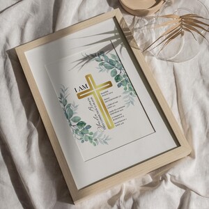 Könnte beinhalten: Ein gerahmter Druck mit einem goldenen Kreuz und grünen Aquarell-Eukalyptusblättern. Der Text lautet I AM, Sandra Brown, FIRST COMMUNION 17.06.2026, sowie verschiedene Bibelverse wie Psalm 139:14, Deuteronomium 7:6, Johannes 1:12, Jeremia 29:11, Römer 8:37 und Johannes 4:16.