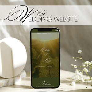 Könnte beinhalten: Ein Smartphone zeigt ein Hochzeitswebsite-Design mit dem Text "Wedding Website". Die Website zeigt ein Landschaftsfoto, die Namen "Olivia & Kevin" und das Datum "Saturday 17th June 2025". Eine weiße Kugel und Blumen befinden sich im Vordergrund.