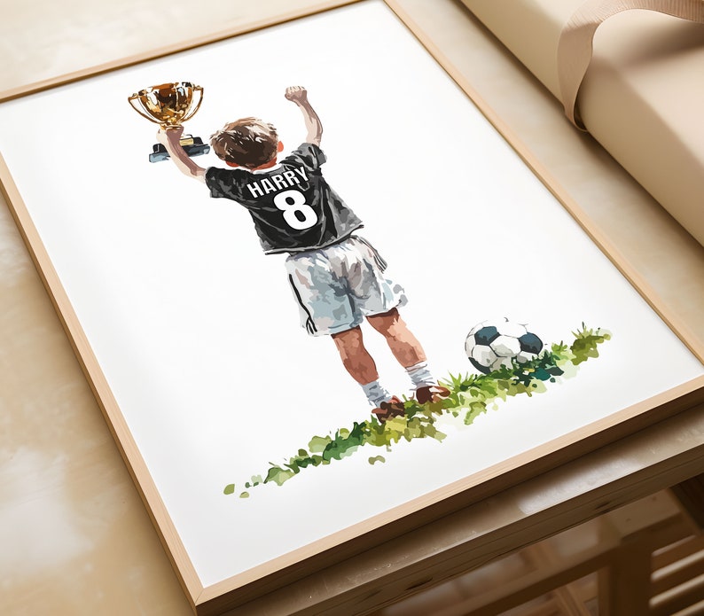 May include: A watercolour painting of a young person holding up a gold trophy, wearing a black football shirt with the name "HARRY" and the number "8" on the back. The person is standing on a green field with a football nearby.