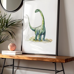 Puede incluir: Impresi&oacute;n en acuarela de un dinosaurio Brontosaurus verde, enmarcada en negro. La obra de arte se exhibe sobre un banco de madera con patas de metal negro, junto a un jarr&oacute;n decorativo y libros. Un espejo redondo cuelga de la pared.