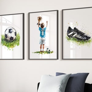 May include: Three framed watercolour paintings depicting a football, a boy holding a trophy and a football boot. The boy is wearing a blue jersey with the number 8 and the name "HARRY" on the back.