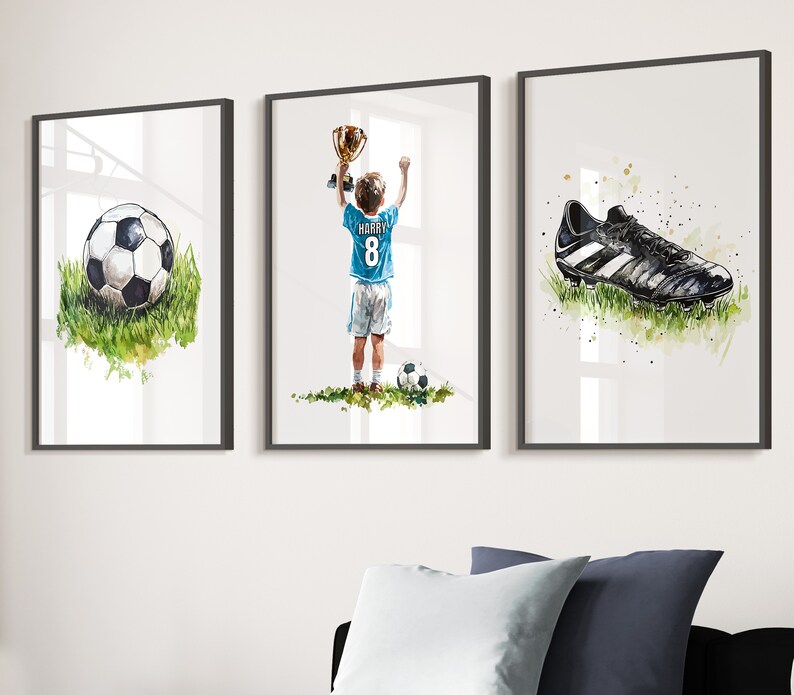 May include: Three framed watercolour paintings depicting a football, a boy holding a trophy and a football boot. The boy is wearing a blue jersey with the number 8 and the name "HARRY" on the back.