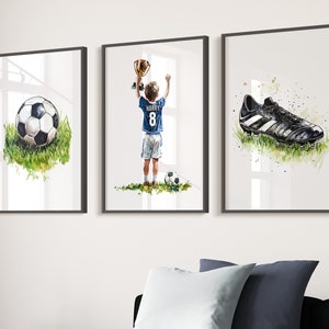 May include: Three framed watercolour paintings depicting a football, a boy holding a trophy and a football boot. The boy is wearing a blue jersey with the number 8 and the name "HARRY" on the back.