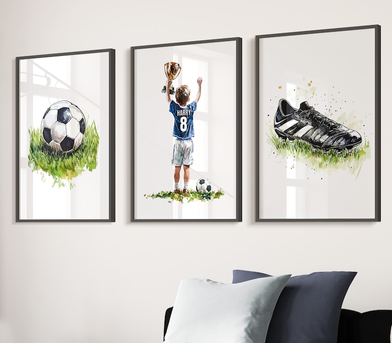 May include: Three framed watercolour paintings depicting a football, a boy holding a trophy and a football boot. The boy is wearing a blue jersey with the number 8 and the name "HARRY" on the back.