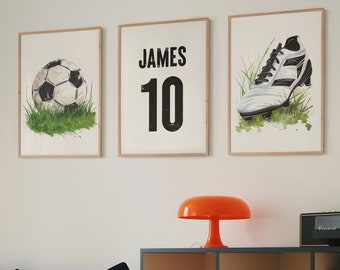 Könnte beinhalten: Drei gerahmte Drucke mit Fußball-Motiv. Der linke Druck zeigt einen weißen und schwarzen Fußball auf grünem Gras. Der mittlere Druck zeigt den Namen "JAMES" und die Nummer "10" in schwarzem Text. Der rechte Druck zeigt einen weißen Fußballschuh mit schwarzen Akzenten auf grünem Gras.