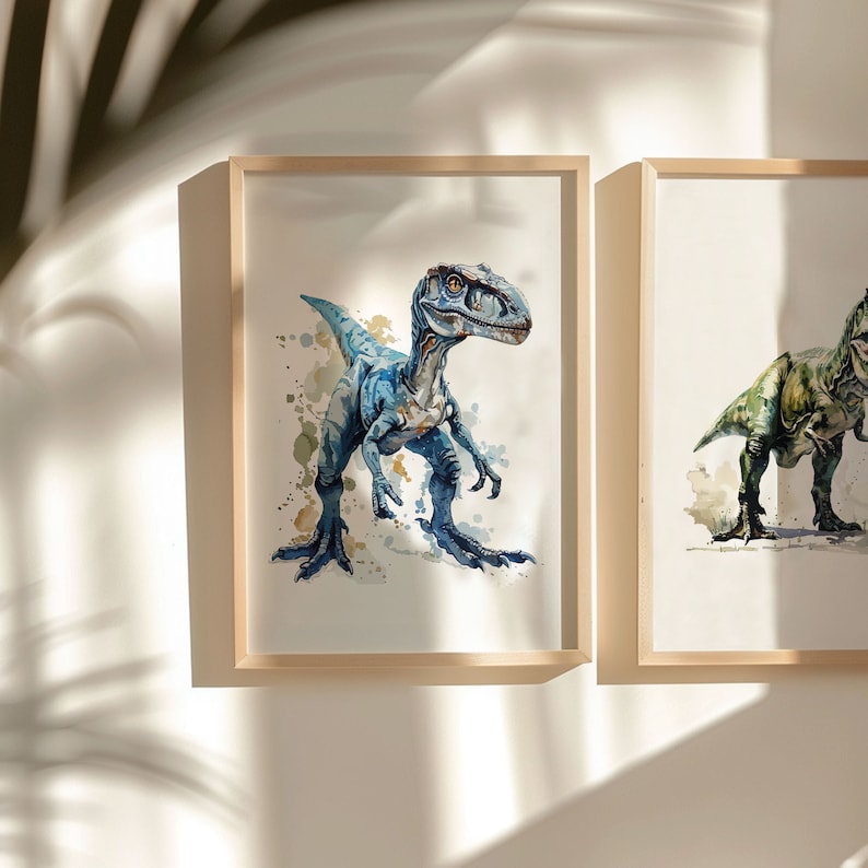 Puede incluir: Dos pinturas de acuarela enmarcadas de dinosaurios. La pintura de la izquierda presenta un velociraptor azul con salpicaduras de acuarela en el fondo. La pintura de la derecha presenta un Tyrannosaurus Rex verde con salpicaduras de acuarela en el fondo.