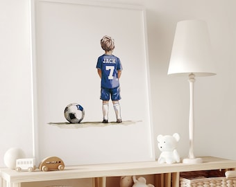 May include: A white framed print of a watercolor illustration of a young boy wearing a blue soccer jersey with the name "JACK" and the number "7" on the back. The boy is standing with his back to the viewer, holding a soccer ball in front of him.