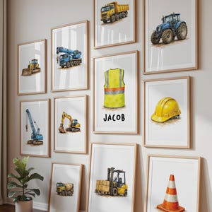 May include: A series of framed watercolour prints depicting construction vehicles and equipment. The prints include a dumper truck, tractor, crane, excavator, cement mixer, forklift, and traffic cone. One print has the name "JACOB" on it.