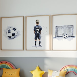 K&ouml;nnte beinhalten: Drei gerahmte Aquarell-Illustrationen eines Fu&szlig;ballspielers, eines Fu&szlig;balls und eines Fu&szlig;balltors. Der Spieler tr&auml;gt ein schwarzes Trikot mit dem Namen "Jack" und der Nummer "7" auf dem R&uuml;cken. Der Fu&szlig;ball ist wei&szlig; mit schwarzen Paneelen. Das Fu&szlig;balltor ist schwarz mit einem wei&szlig;en Netz.