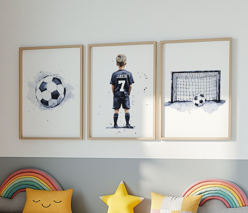K&ouml;nnte beinhalten: Drei gerahmte Aquarell-Illustrationen eines Fu&szlig;ballspielers, eines Fu&szlig;balls und eines Fu&szlig;balltors. Der Spieler tr&auml;gt ein schwarzes Trikot mit dem Namen "Jack" und der Nummer "7" auf dem R&uuml;cken. Der Fu&szlig;ball ist wei&szlig; mit schwarzen Paneelen. Das Fu&szlig;balltor ist schwarz mit einem wei&szlig;en Netz.