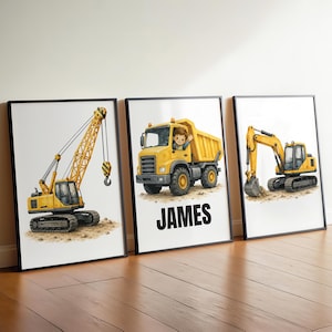 May include: Three framed wall art prints featuring yellow construction vehicles on a white background. The left print shows a crane, the centre print shows a dump truck with a person in the cab and the name JAMES, and the right print shows an excavator.