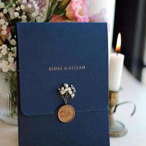Faire-part de mariage élégant en acrylique doré avec enveloppe bleu marine, carte en acrylique doré, cachet de cire, fleurs séchées naturelles et touches délicates