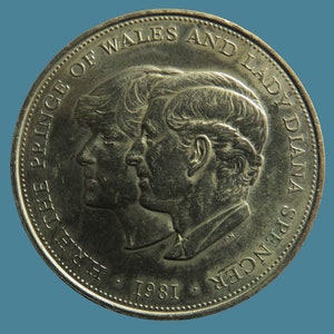 Puede incluir: Una moneda conmemorativa de plata con los perfiles del Príncipe Carlos y Lady Diana Spencer, con el texto "HRH THE PRINCE OF WALES AND LADY DIANA SPENCER 1981".