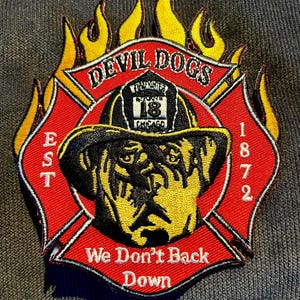 Könnte beinhalten: Gestickter Aufnäher mit einem Rottweiler, der einen Feuerwehrhelm trägt. Der Aufnäher ist rot mit gelben Flammen, den Worten "DEVIL DOGS" und "We Don't Back Down". Er enthält auch den Text "EST 1872" und "CHICAGO 18".