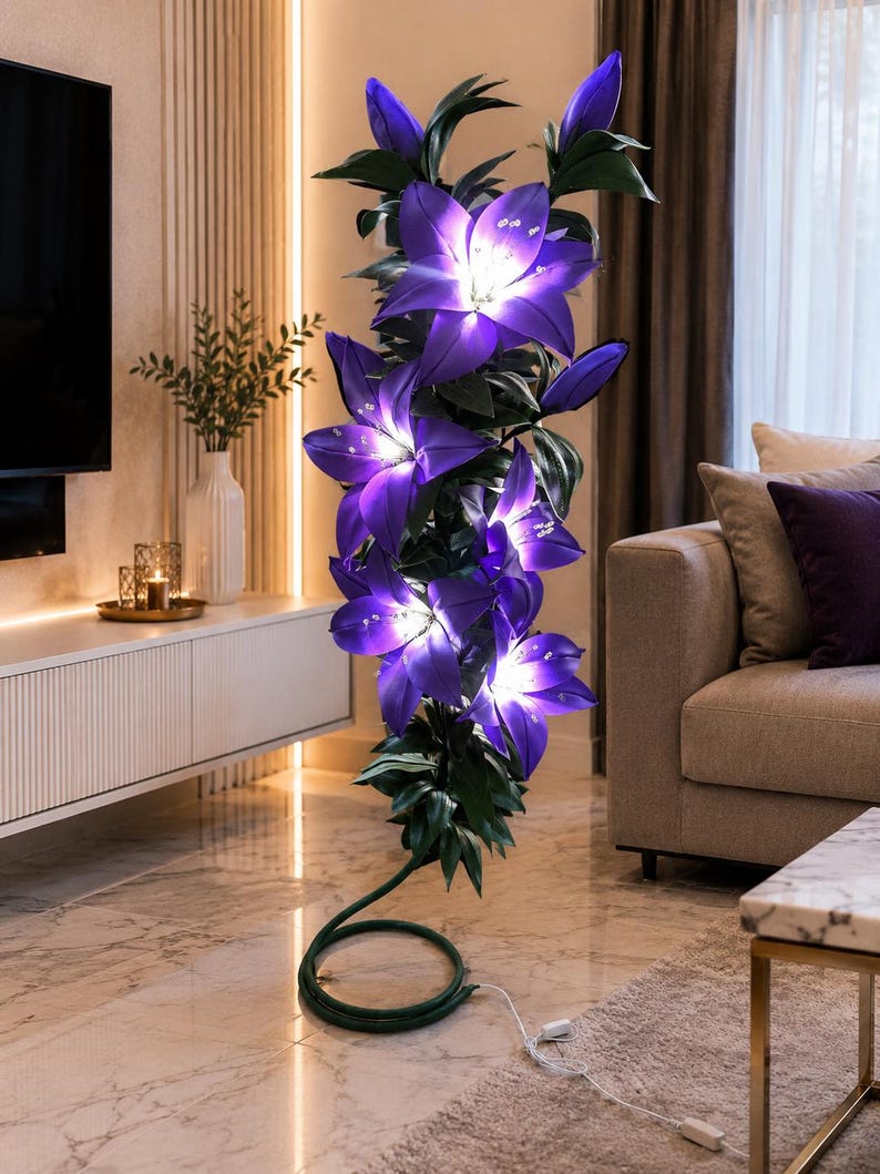 Puede incluir: Una l&aacute;mpara de pie alta con forma de racimo de flores de lirio de color p&uacute;rpura vibrante con hojas verdes. Los p&eacute;talos est&aacute;n iluminados desde el interior, emitiendo un brillo blanco intenso. La base es un tallo verde enrollado con cable.