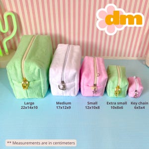 Puede incluir: Conjunto de cinco estuches de felpa con cremallera en varios tamaños y colores: verde claro, blanco, rosa y un pequeño estuche llavero rosa. Los estuches tienen cremalleras doradas o plateadas. Medidas en centímetros.