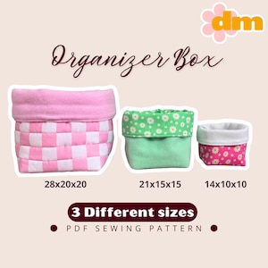 May include: Three fabric organiser boxes in varying sizes. The largest is pink and white chequered, measuring 28x20x20 cm. The medium box is green with a daisy print, and the smallest is pink with a floral pattern. Text reads "Organizer Box" and "3 Different sizes".
