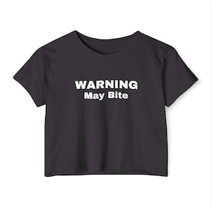 Puede incluir: Una camiseta negra recortada con texto blanco que dice "WARNING May Bite".