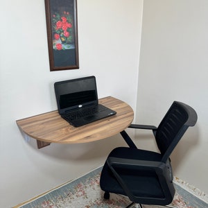 Pu&ograve; includere: Una piccola scrivania semicircolare in legno, montata a parete, con un laptop sopra. Una sedia da ufficio nera &egrave; posizionata sotto la scrivania. Un dipinto incorniciato di rose rosse &egrave; appeso al muro. La stanza ha un tappeto con motivi floreali.