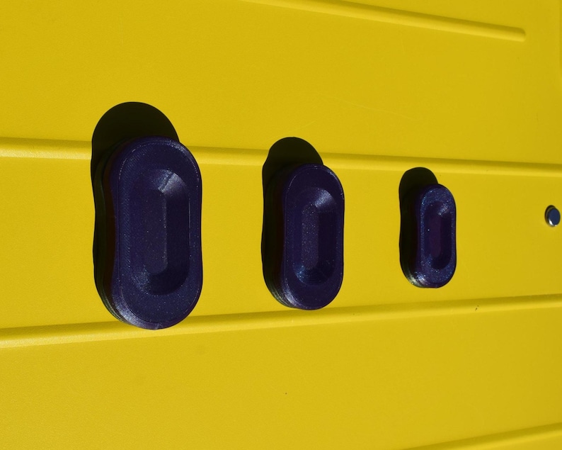 May include: Three dark blue, oval-shaped objects are set into a bright yellow surface. The objects are of varying sizes, with the largest on the left and the smallest on the right. The yellow surface has horizontal lines.